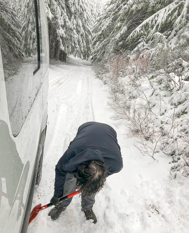 Alex shoveling snow from under Sprinter van to get traction again