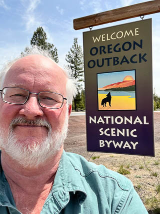 Barry K7BWH standing in front of the Oregon Outback road sign